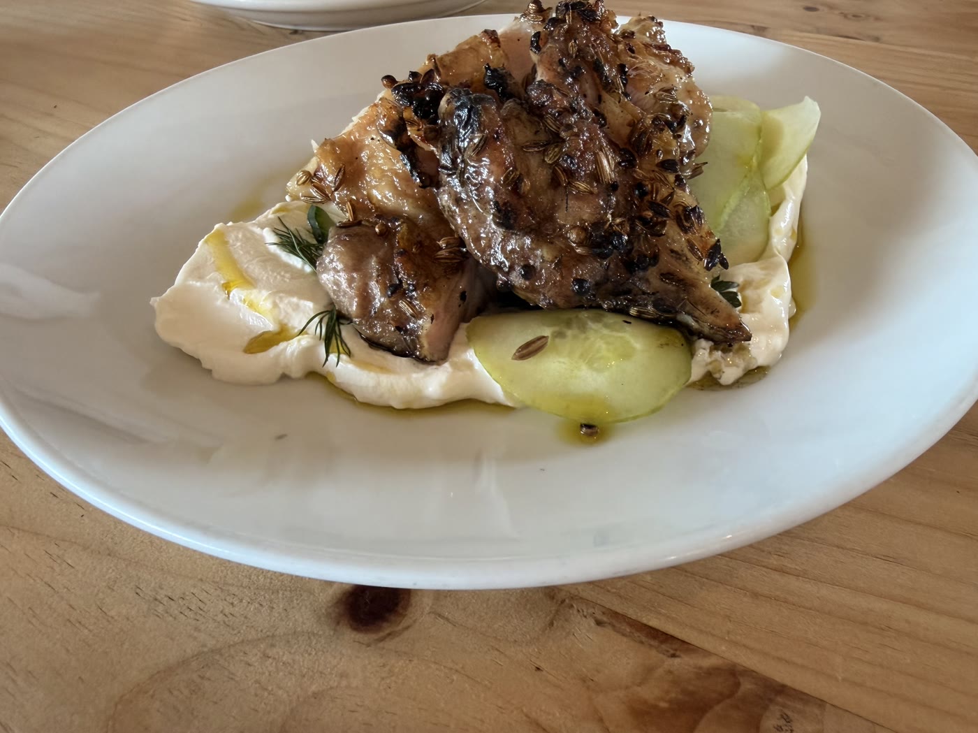 Garlic and herb chicken thighs over labneh and cucumber at Kinsbrook’s restaurant