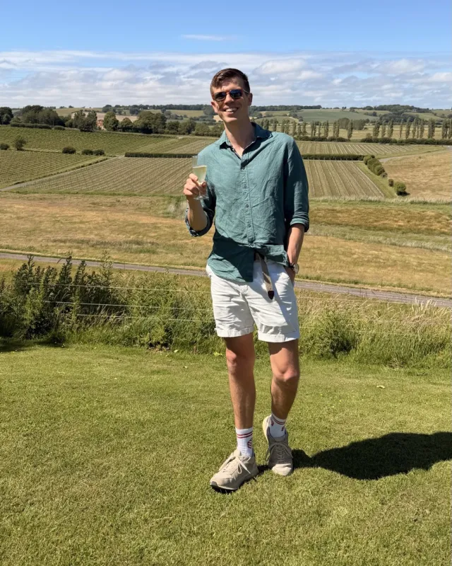 Stephen holding a glass of wine in front of the vines at Charles Palmer Vineyards